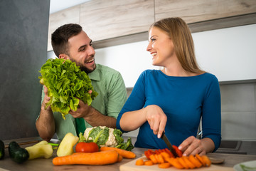 Young couple is preparing meal in their kitchen. 