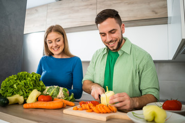 Young couple is preparing meal in their kitchen. 