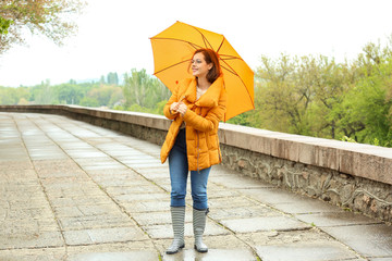 Beautiful young woman with umbrella outdoors on rainy day