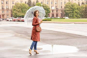 Beautiful young woman with umbrella outdoors on rainy day