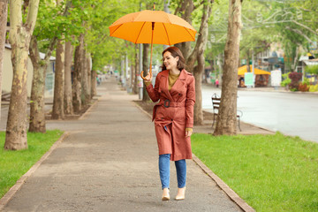 Beautiful young woman with umbrella outdoors on rainy day