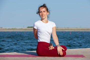 Fototapeta premium The girl is engaged in meditation on coast of lake