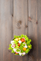 Healthy salad in bowl on wooden background. Top view