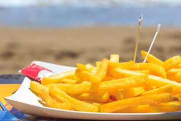 Fried french fries on the beach against the background of the sea