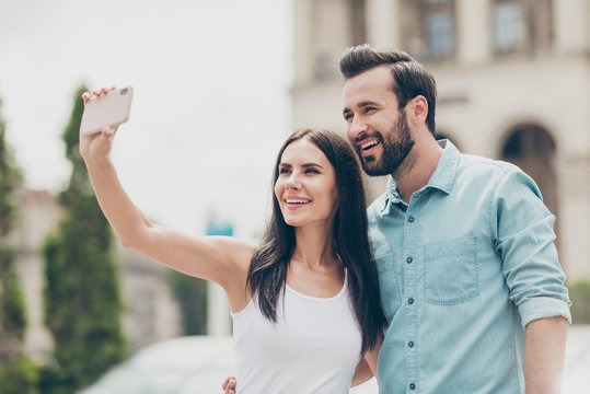 Portrait of charming cute lovely romantic married people youth hold hand blog bloggers make photos vacation weekend tour meeting bearded video call mobile top singlet shirt blue denim jeans building