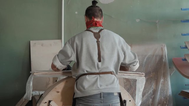 Worker glues veneer on a wooden part apt glue press machine plywood workshop factory. Craftman man equipment