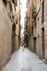 Fototapeta na wymiar Barcelona, Spain - 25th July 2017 - People or tourists walking through a long alley to the shops