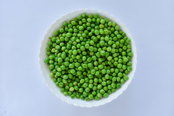 Green peas in a white bowl on a white background