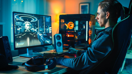 Cheerful Gamer Playing First-Person Shooter Online Video Game on His Powerful Personal Computer....