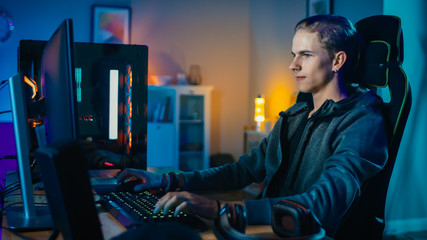 Concentrated Gamer Playing First-Person Shooter Online Video Game on His Powerful Personal Computer. Room and PC have Colorful Neon Led Lights. Cozy Evening at Home.