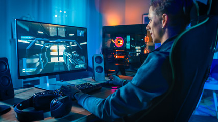 Happy Gamer Playing First-Person Shooter Online Video Game on His Powerful Personal Computer. Room...