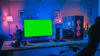 Powerful Personal Computer Gamer Rig with Mock Up Green Screen Monitor Stands on the Table at Home. Cozy Room with Modern Design is Lit with Pink Neon Light. © Gorodenkoff