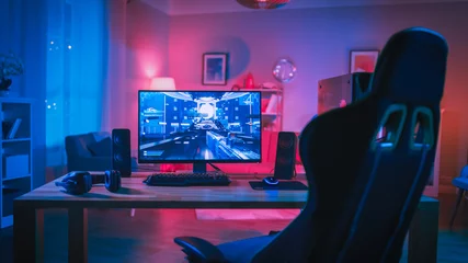 Fotobehang Gaming Powerful Personal Computer Gamer Rig with First-Person Shooter Game on Screen. Monitor Stands on the Table at Home. Cozy Room with Modern Design is Lit with Pink Neon Light.  © Gorodenkoff
