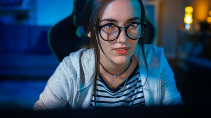 Excited and Pretty Gamer Girl in Glasses is Playing Online Video Game on Her Personal Computer....