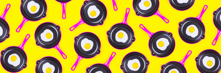 Creative food pattern with fried eggs on pink pans over yellow background. Top view. Creative pattern in minimal style. Flat lay. Banner.