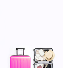 Open pink suitcase packed for travelling on light grey background with place for text. Hat, glasses, sandals, swimsuit, bag, passport in open suitcase.	