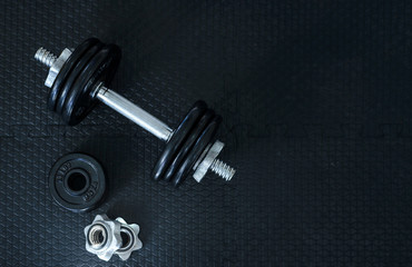 Obraz na płótnie Canvas Top view of Iron dumbbells or weights on black floor with copy space for text. Flat lay composition. Health care concept.