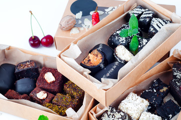Sweet dessert candies handmade with various healthy fillings. in a craft box on a white background.