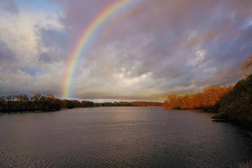 Naklejka premium Colorful rainbow in the sky over lake