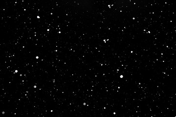 falling snow on a black background, snowfall at night, white chaotic spots on a black background