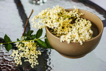 Elderberry flowers on table, in bowl.