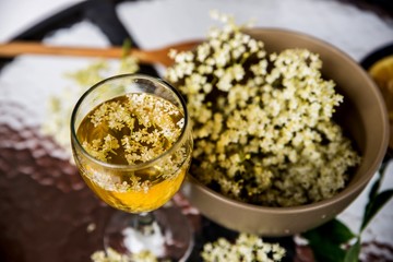 Glass and bowl with elderberry syrup and flowers.