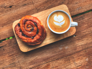 Serving size.heart love piccolo  latte art and cinnamon roll on the wooden tray , vintage style