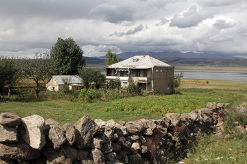 A village house with a stone fence in the village of Foka on the shore of the mountain lake Paravani © Nadzeya