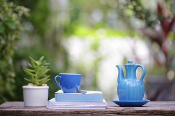 Blue coffee cup with small plant pot and notebooks at outdoor