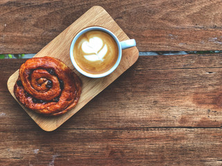 Serving size.heart love piccolo  latte art and cinnamon roll on the wooden tray , vintage style