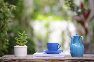 Blue coffee cup with small plant pot and notebooks at outdoor