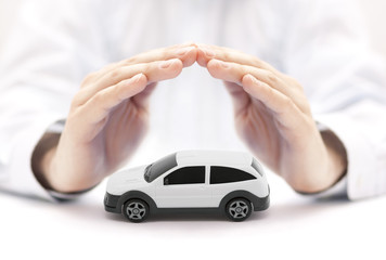 Car insurance concept with white car toy covered by hands 