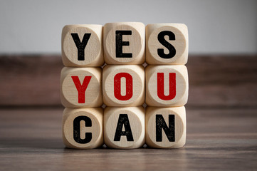 Cubes and dice with slogan Yes you can on wooden background