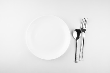 Empty white plate, spoon and knife isolated on white background. diet concept.