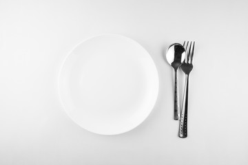 Empty white plate, spoon and knife isolated on white background. diet concept.