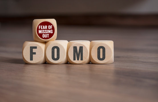 Cubes and dice with FOMO Fear of missing out on wooden background