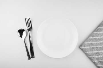 Empty white plate, spoon and knife isolated on white background. diet concept.