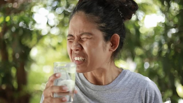 Young Asian woman with sensitive teeth, woman drinking cold drink