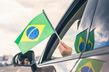 Woman or Girl Holding Flag of Brazil from the open car window. Concept