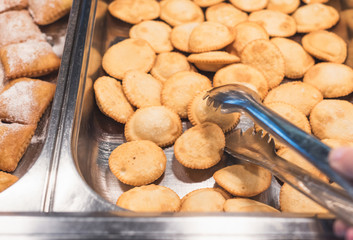 Woman choosing Cretan Sweet Pastries on a breakfast in a hotel restaurant.  Breakfast Buffet Concept