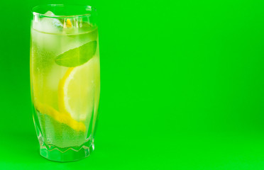 A glass of lemonade with mint on a bright green background. Cooling drink. Summer.Copy space.