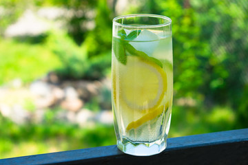  A glass of lemonade with mint on the background of fresh summer green grass. Cooling drink. Summer.