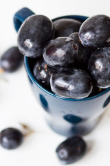 A bunch of big black grapes in a blue cup