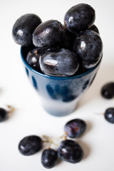 A bunch of big black grapes in a blue cup