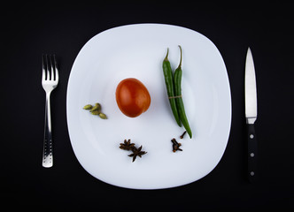 Empty white plate, spoon, knife and spices isolated on black background. diet concept.