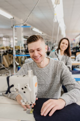 Obraz premium close up photo of a young man and other seamstresses sewing with sewing machine in a factory