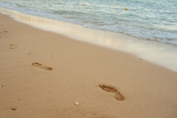 Footprints of human feet on the sand near the water on the beach