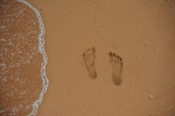 Footprints of human feet on the sand near the water on the beach