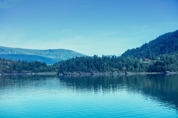 Rocky shore of a mountain lake in autumn. Beautiful nature of Norway. Reflection on the lake. Blue toned.