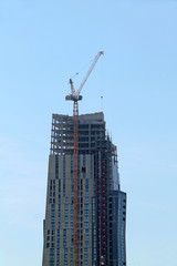 Fototapeta na wymiar A Very High Jib Crane on a Tall Building Construction.